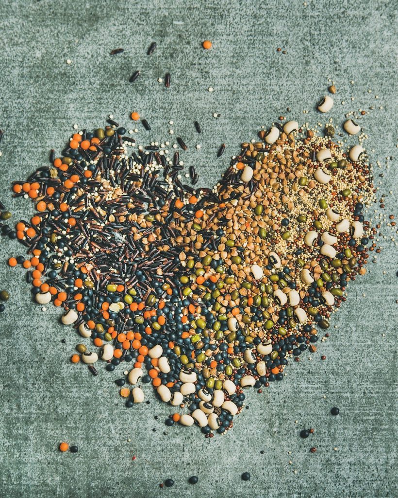 Various raw grains, beans and cereals in shape of heart